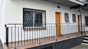 Un edificio residencial con balcón, una ventana con rejas y una puerta.