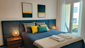 Une chambre moderne avec un grand lit, deux tables de chevet et une vue sur l’extérieur.