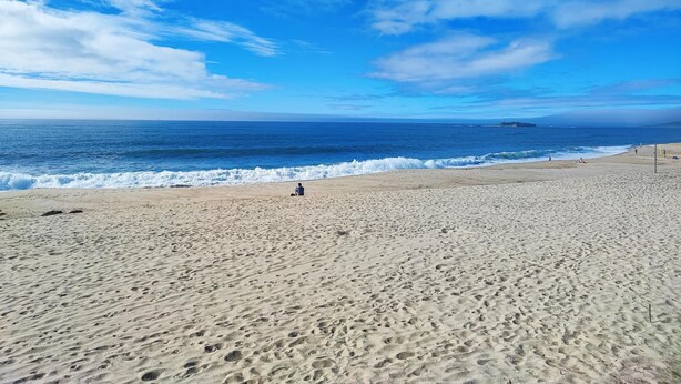 Une plage avec un ciel dégagé et une mer calme.