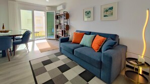 Un salon moderne avec un canapé bleu, un tapis noir et blanc et un coin repas comprenant une table et des chaises.