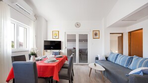 Una sala moderna con comedor, televisor de pantalla plana y sofá con cojines a rayas.