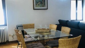 A dining area with a glass table surrounded by wicker chairs, a blue sofa, and a framed picture on the wall. - LA TERRAZZA DI AIDA (Verona)