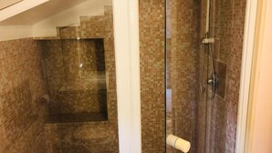 A shower area with a glass door, tiled walls, and a showerhead. - LA TERRAZZA DI AIDA (Verona)