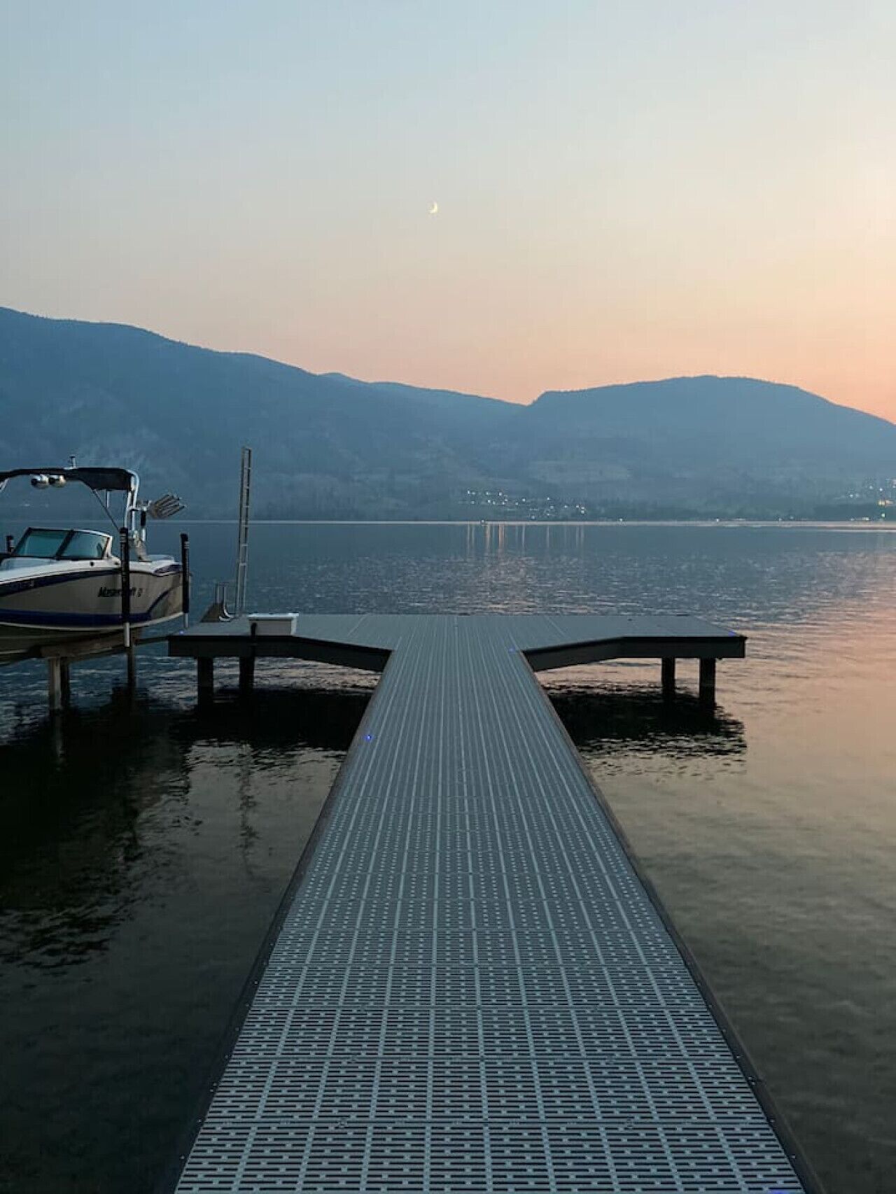 A dock extending into calm water with a boat moored on the left.