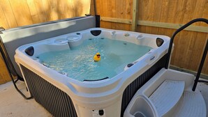 Ein Whirlpool mit Schwimmdackel, einer kleinen Stufe und einem Holzzaun im Hintergrund.