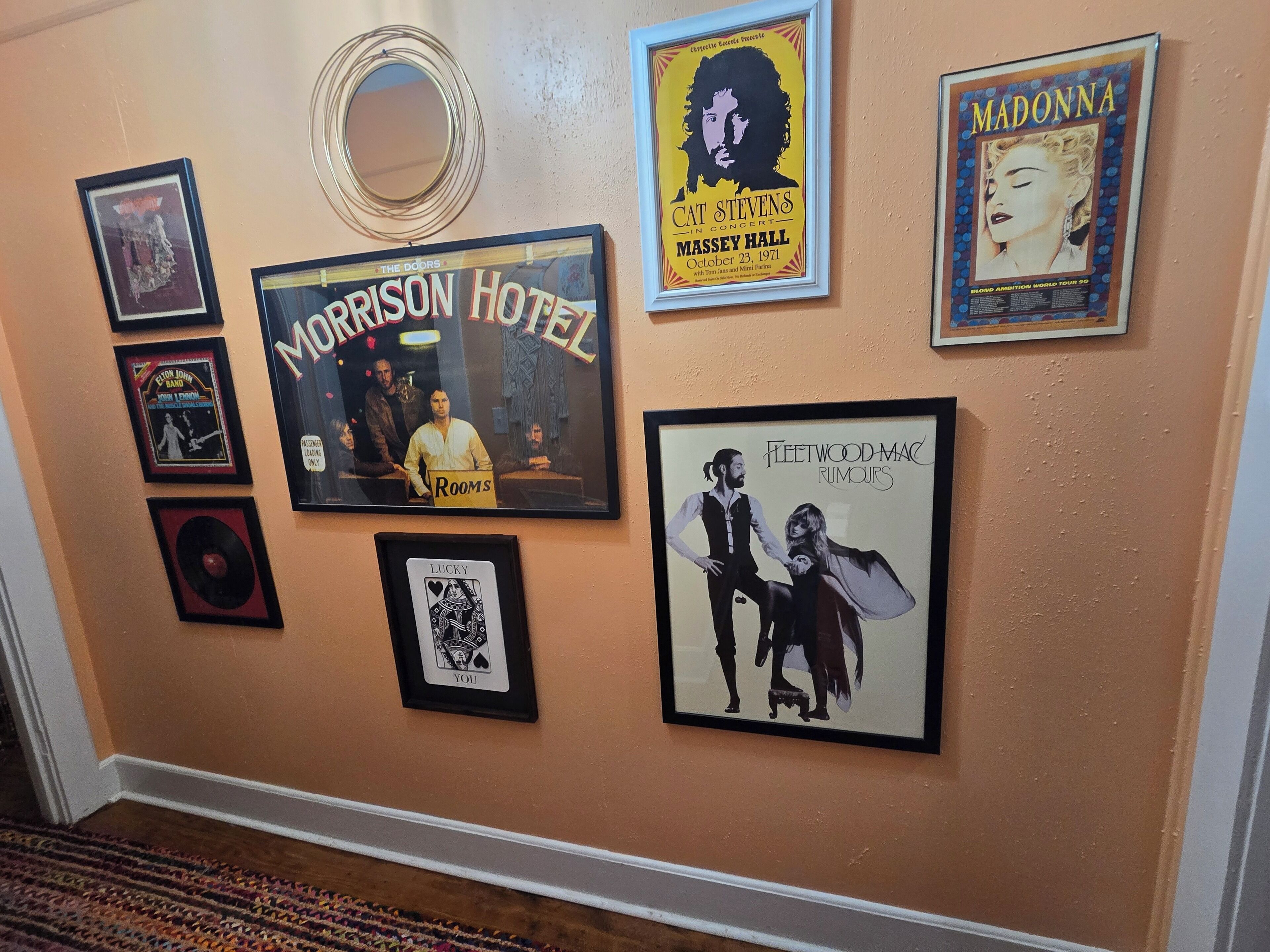 A wall with various framed posters and a mirror.