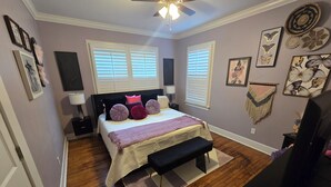 Ein Schlafzimmer mit Bett, Nachttischen, einer Bank und Wanddekorationen.