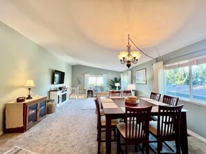 Relax in this stylish living room with a high ceiling, dining area, and mounted TV.