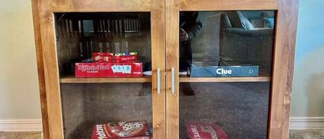 A wooden cabinet with glass doors containing board games.