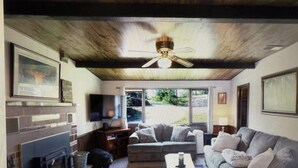A living room with a fireplace, a sofa, a coffee table, and a television. - Charming 2-bedroom cottage lake property with kayaks firepit and Great fishing! (Elcho)