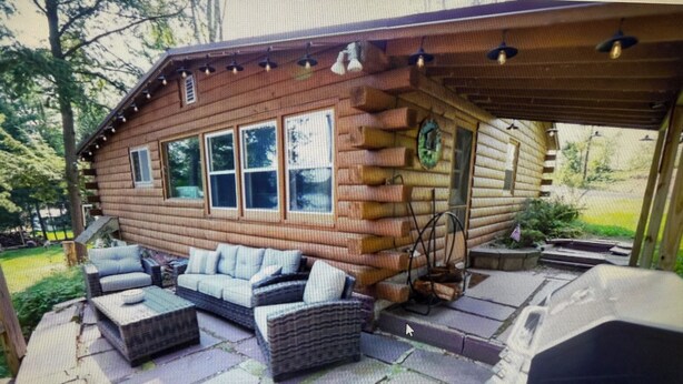 A log cabin with a patio area featuring outdoor furniture and a grill. - Charming 2-bedroom cottage lake property with kayaks firepit and Great fishing! (Elcho)