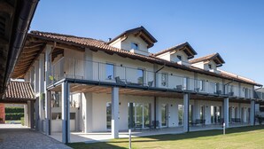 Un edificio moderno con una zona esterna coperta, diversi balconi e un ampio patio.