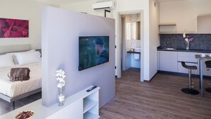 Una camera d'albergo moderna con un letto, una TV, un angolo cottura e un'area pranzo.