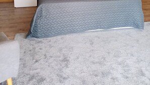 A modern bedroom with a large bed, a wooden nightstand, and a grey headboard.