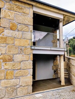 A stone building with a glass door and a staircase leading to an upper level.