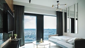 A modern bedroom with a city view, a glass coffee table, and a minimalist design. - Global Apartments (Katowice)