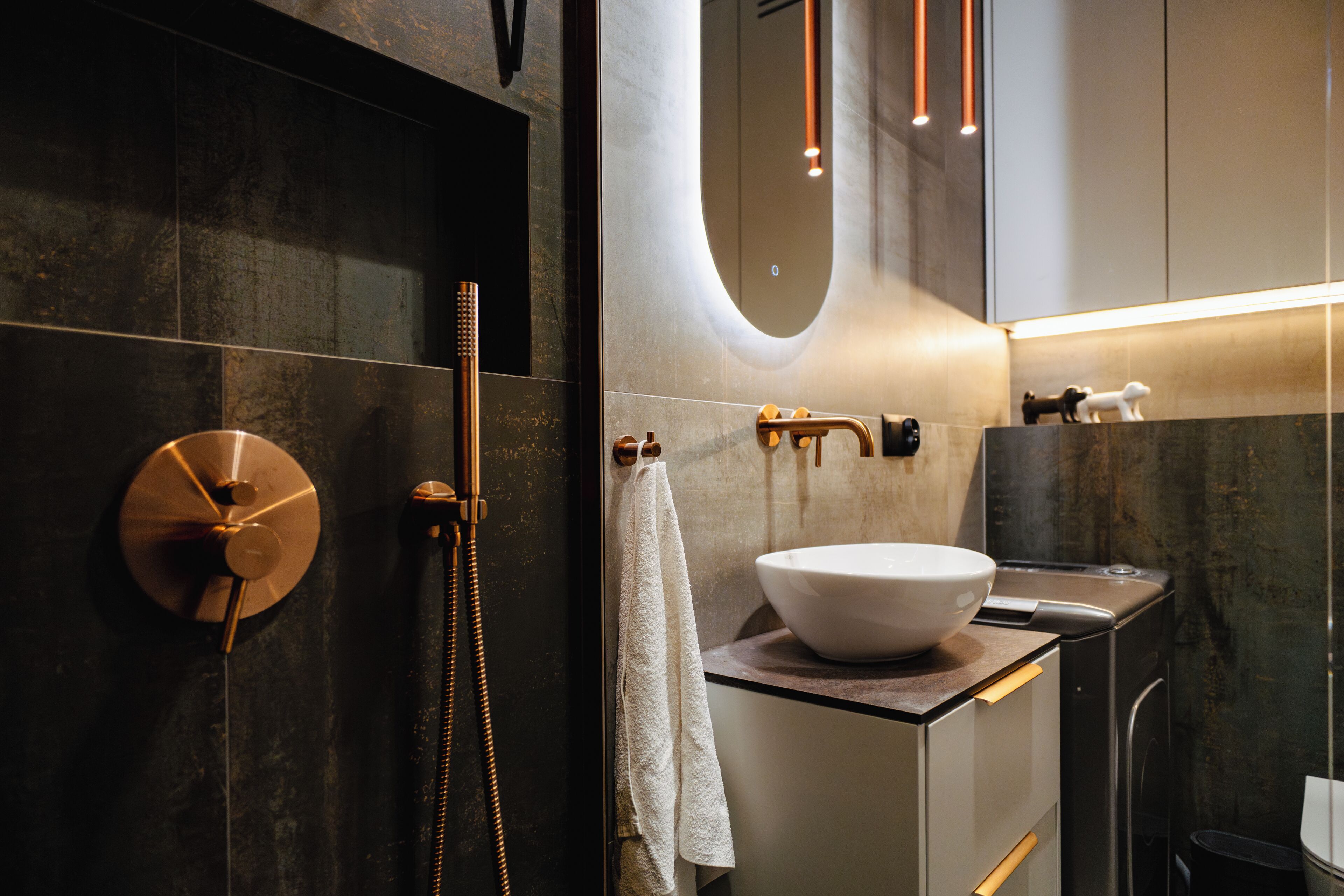 A modern bathroom with a large mirror, a round sink, and a shower with a handheld showerhead.