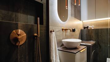 A modern bathroom with a large mirror, a round sink, and a shower with a handheld showerhead.