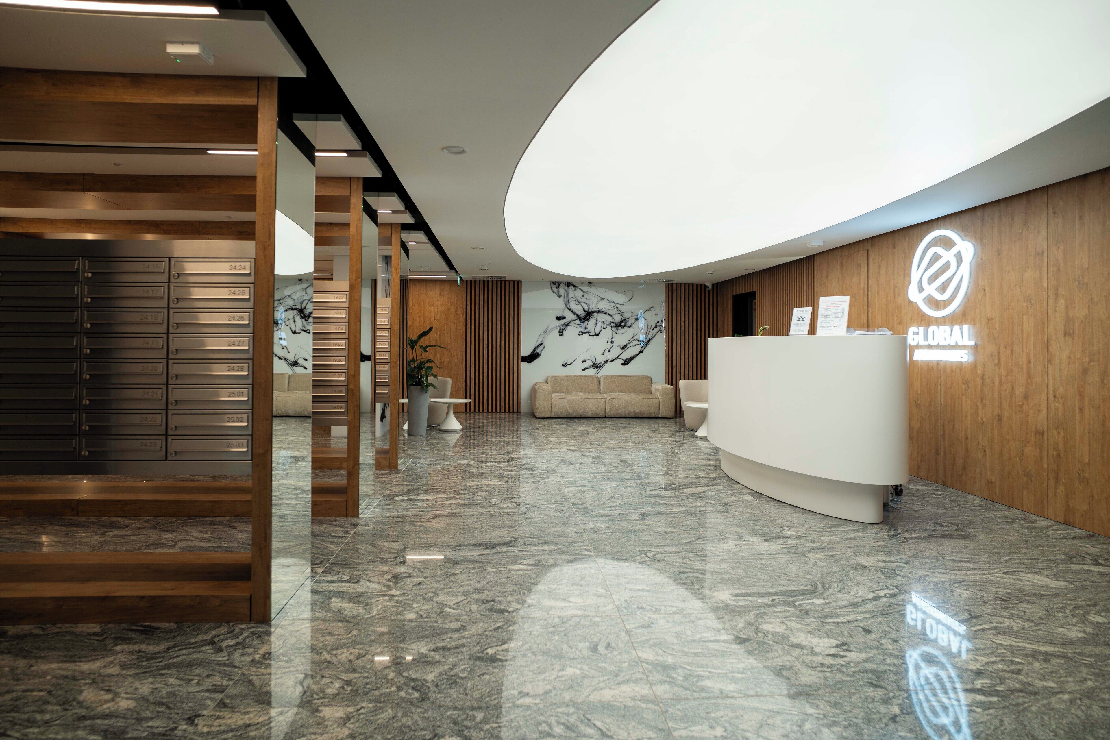 A modern reception area with a marble floor, wooden paneling, a reception desk, and a wall-mounted sign.