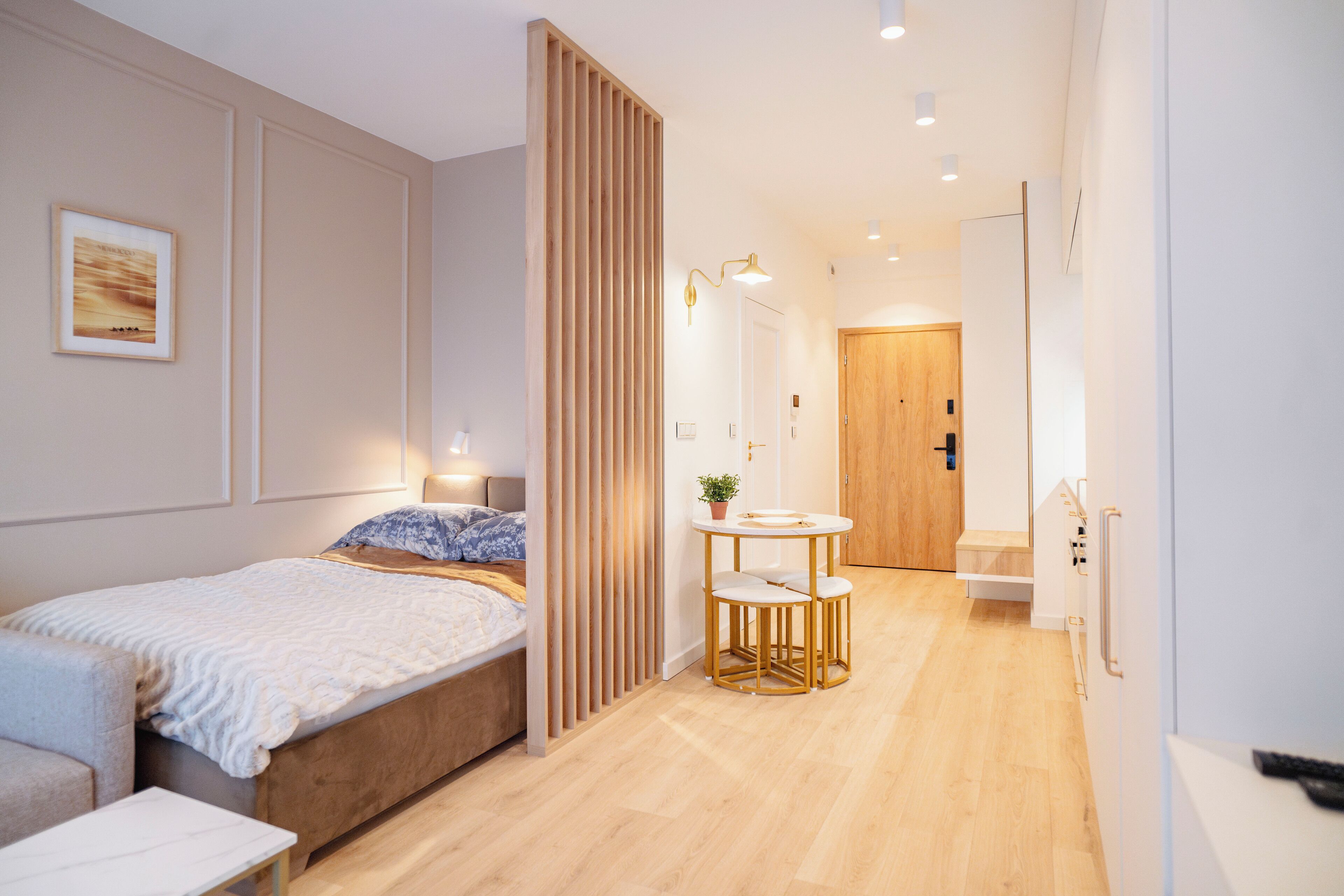 Un dormitorio moderno con cama, mesita de noche y una pequeña mesa redonda con sillas.