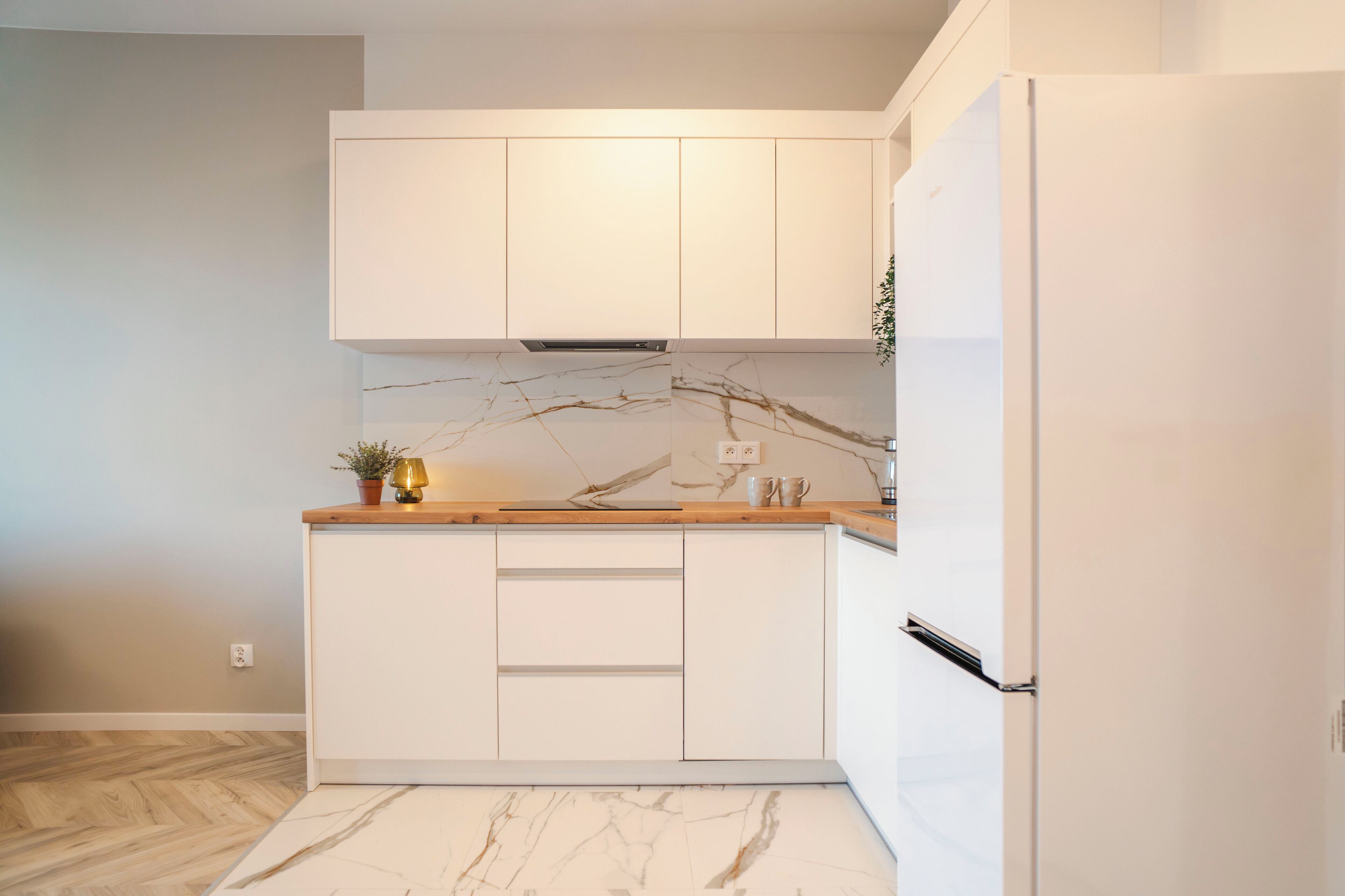 Eine moderne Küche mit weißen Schränken, einer Marmor-Spritzschutzwand und einer Holzarbeitsplatte.