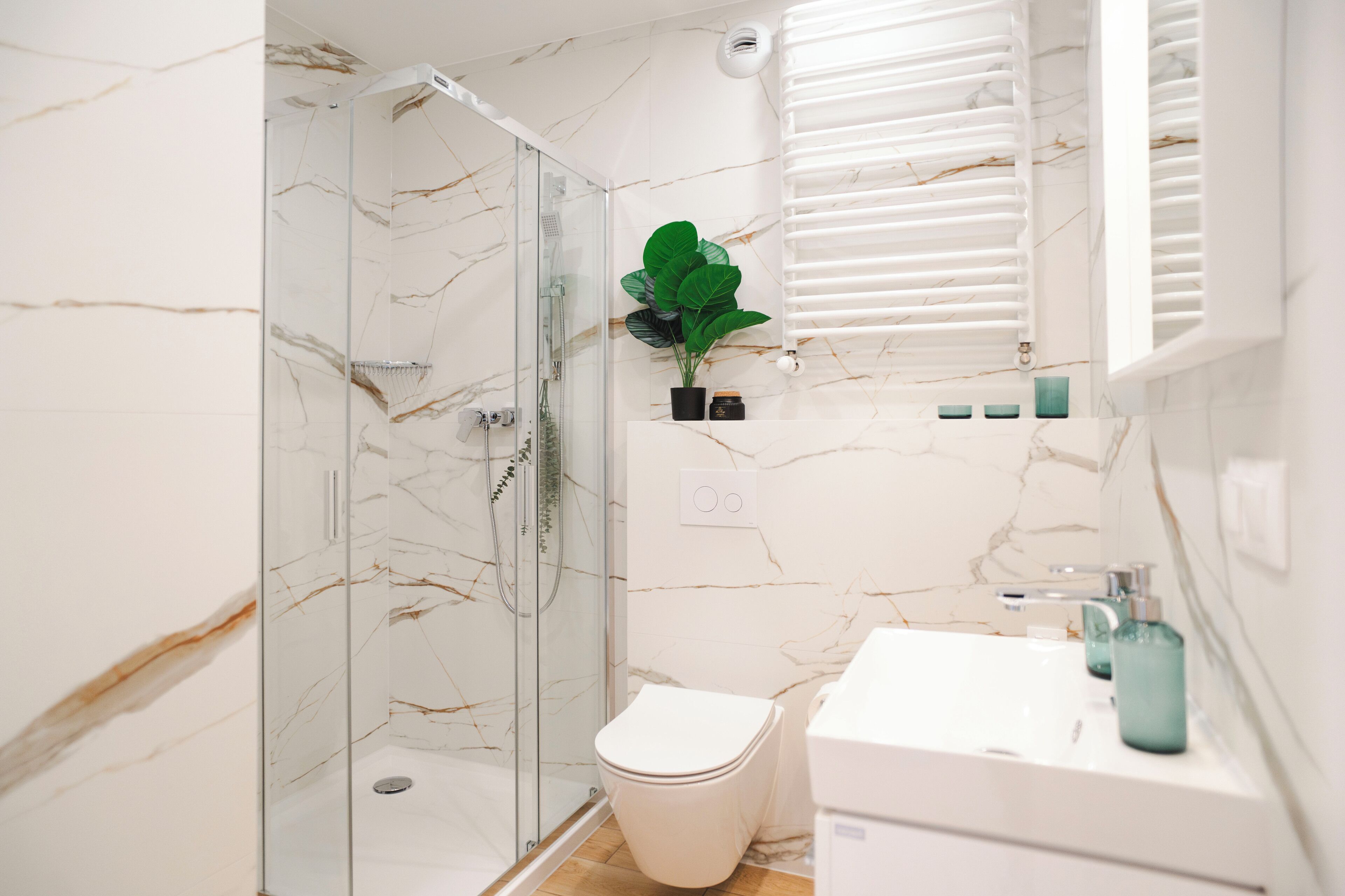 Un baño con ducha de vidrio, inodoro y lavamanos con espejo.