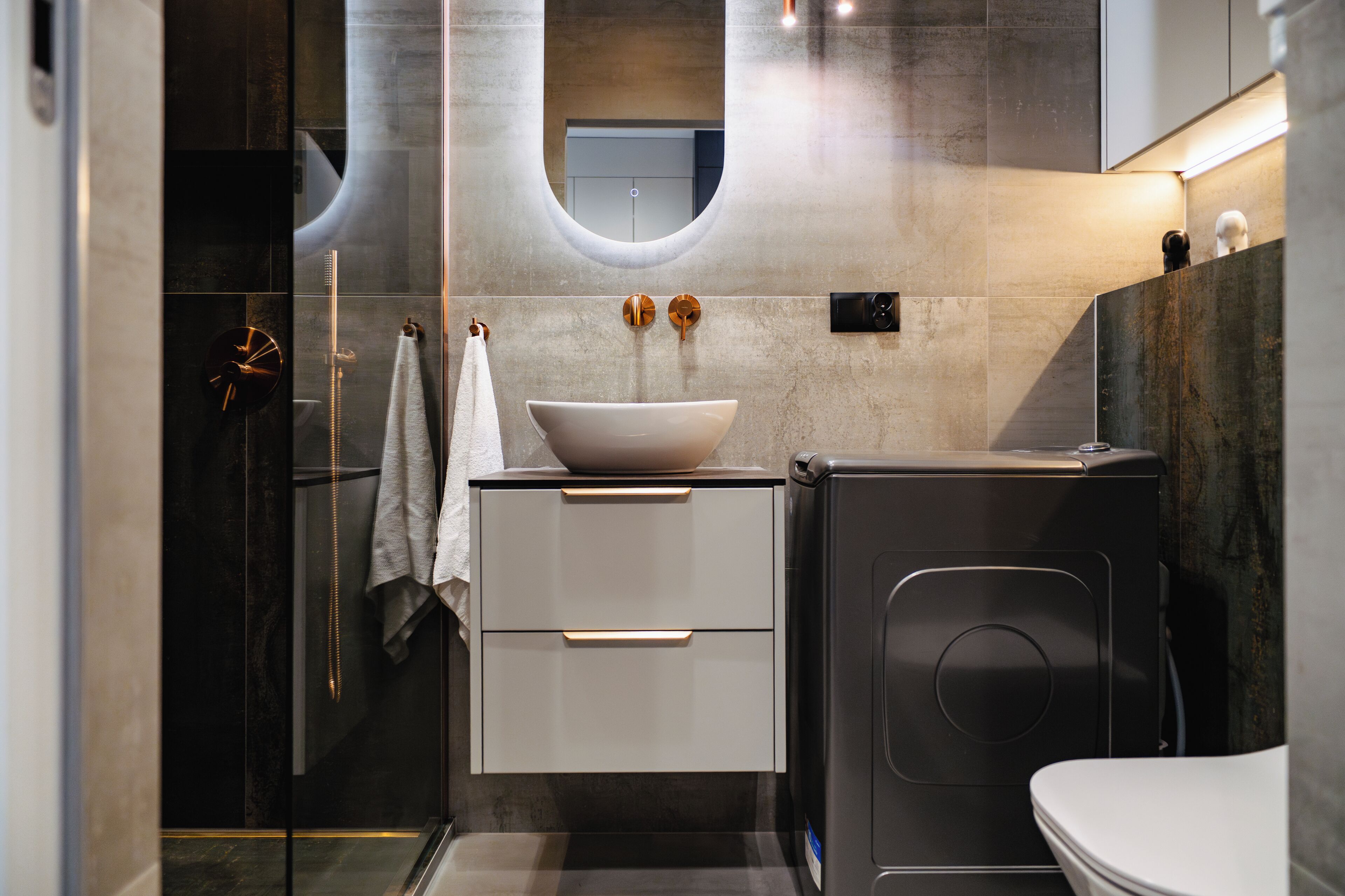 A modern bathroom with a large mirror, a white sink, and a toilet.