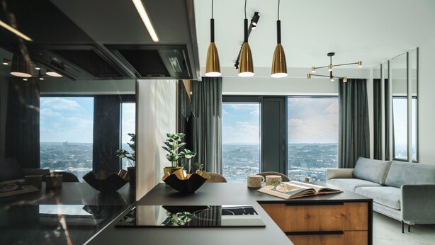 A modern kitchen with a large island, pendant lights, and a view of the city. - Global Apartments (Katowice)