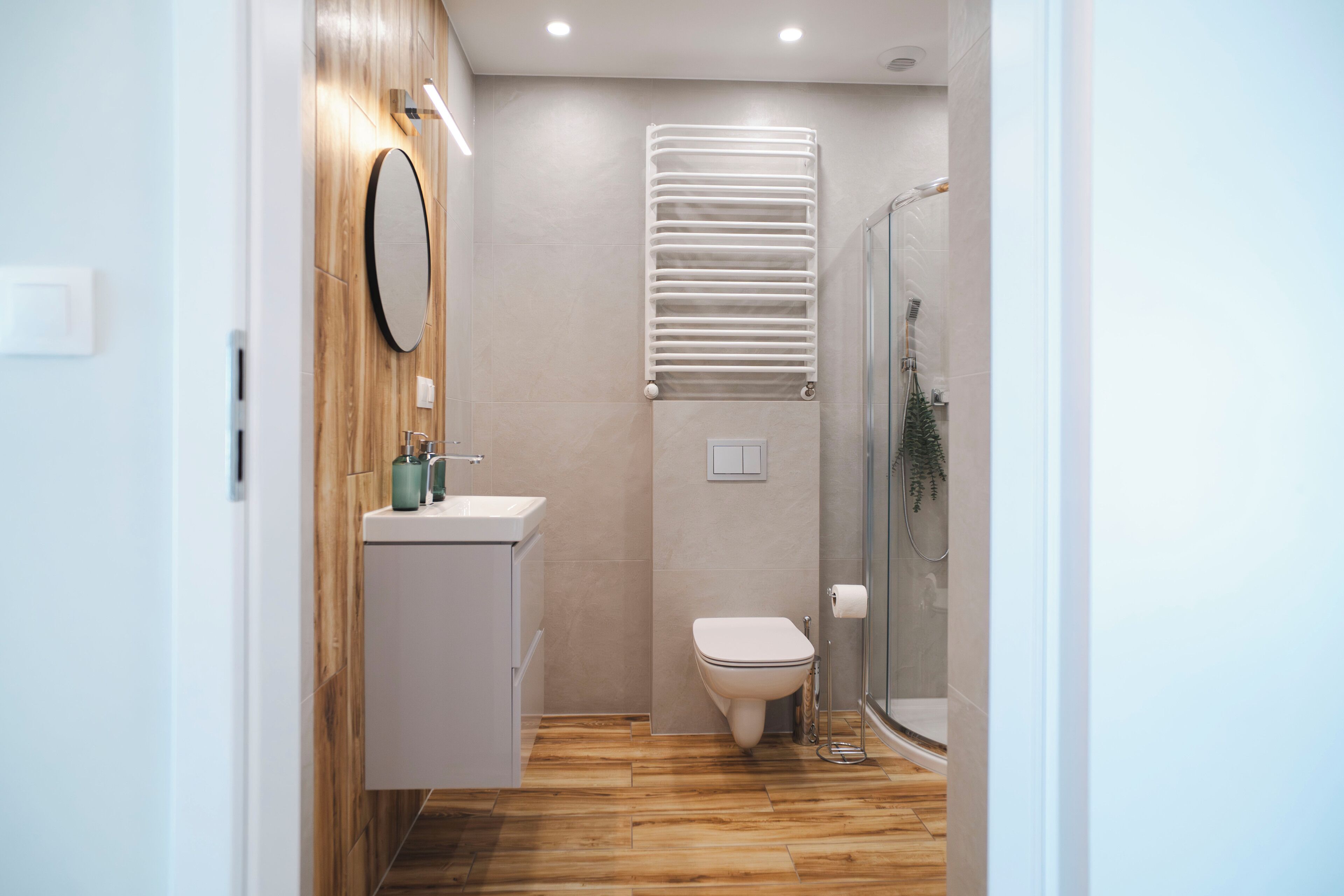 A modern bathroom with a wooden vanity, a toilet, and a glass shower enclosure.