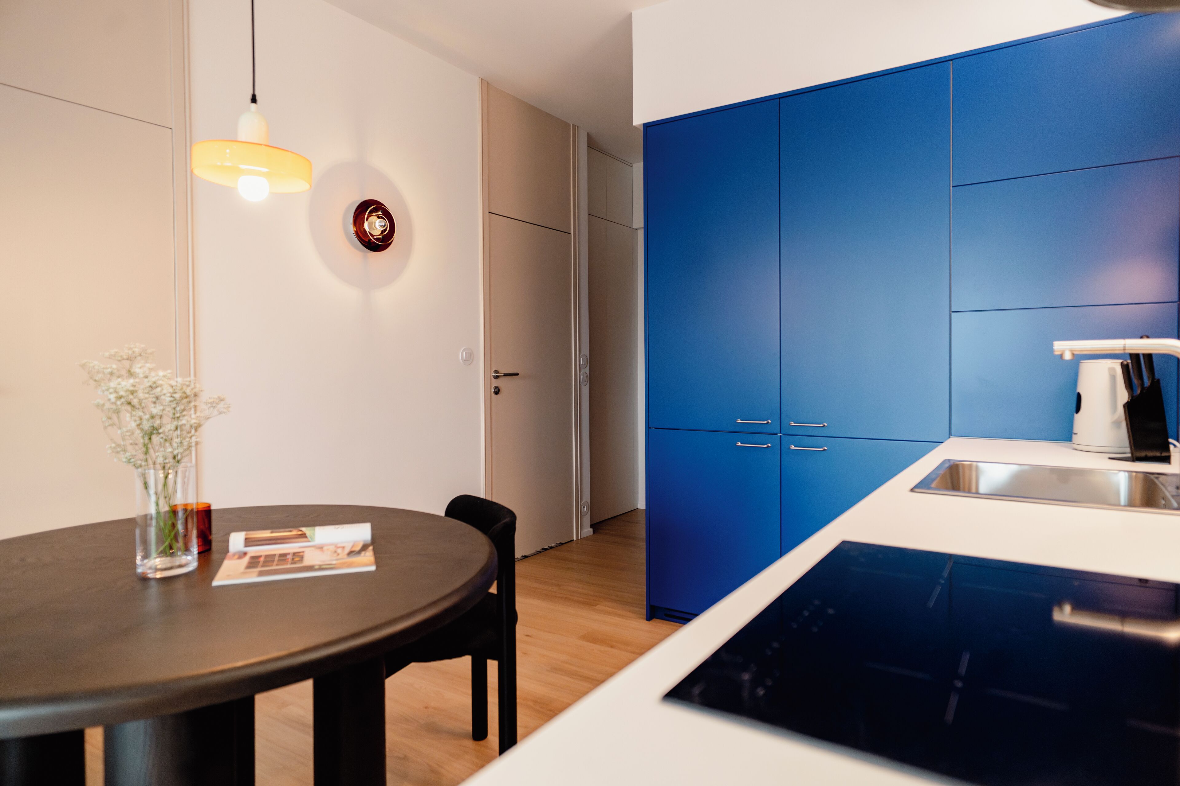 A modern kitchen with blue cabinets, a white countertop, and a built-in dishwasher.