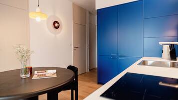 A modern kitchen with blue cabinets, a white countertop, and a built-in dishwasher.