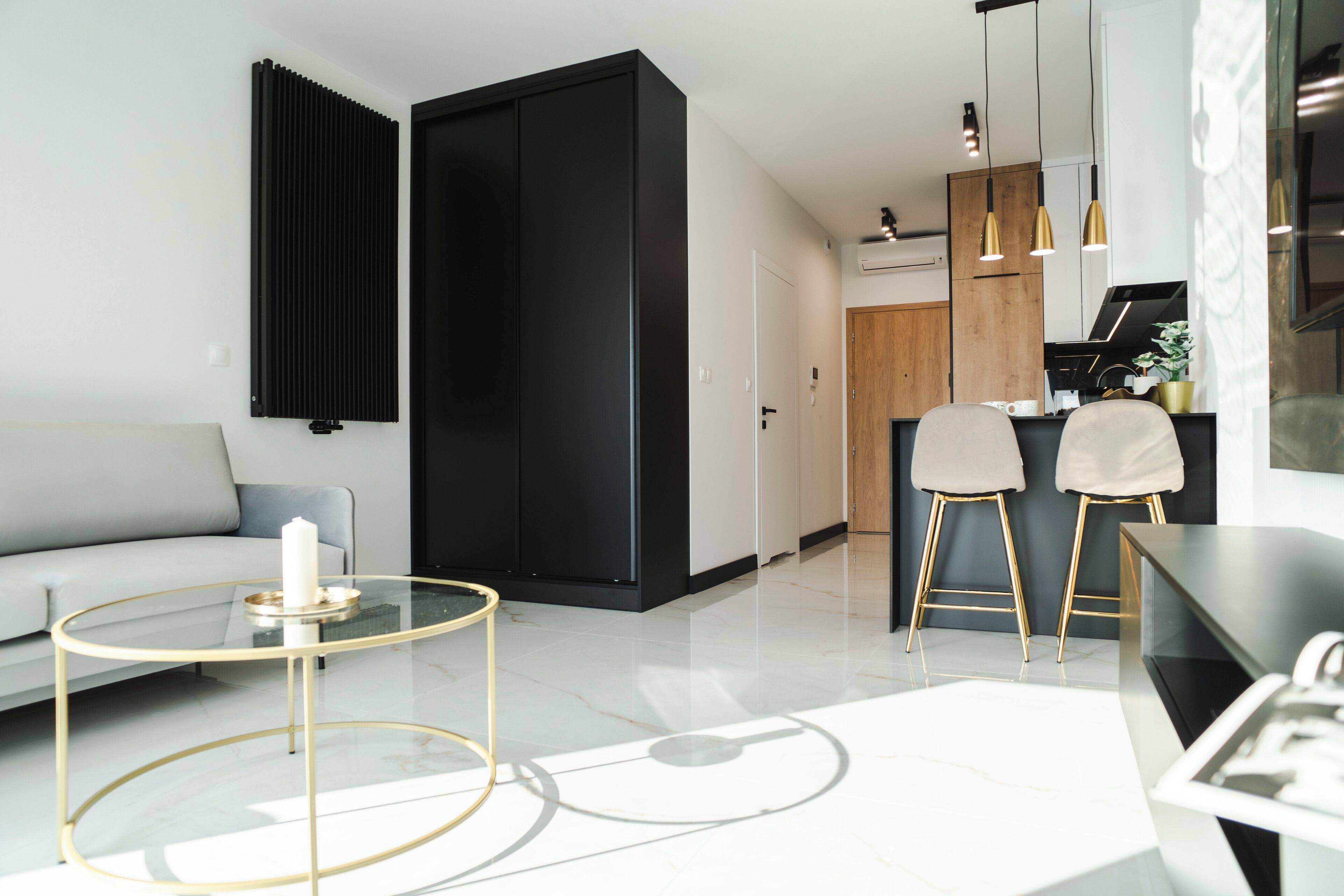 Een moderne woonkamer met een glazen salontafel, een bank en een keuken met barstoelen.
