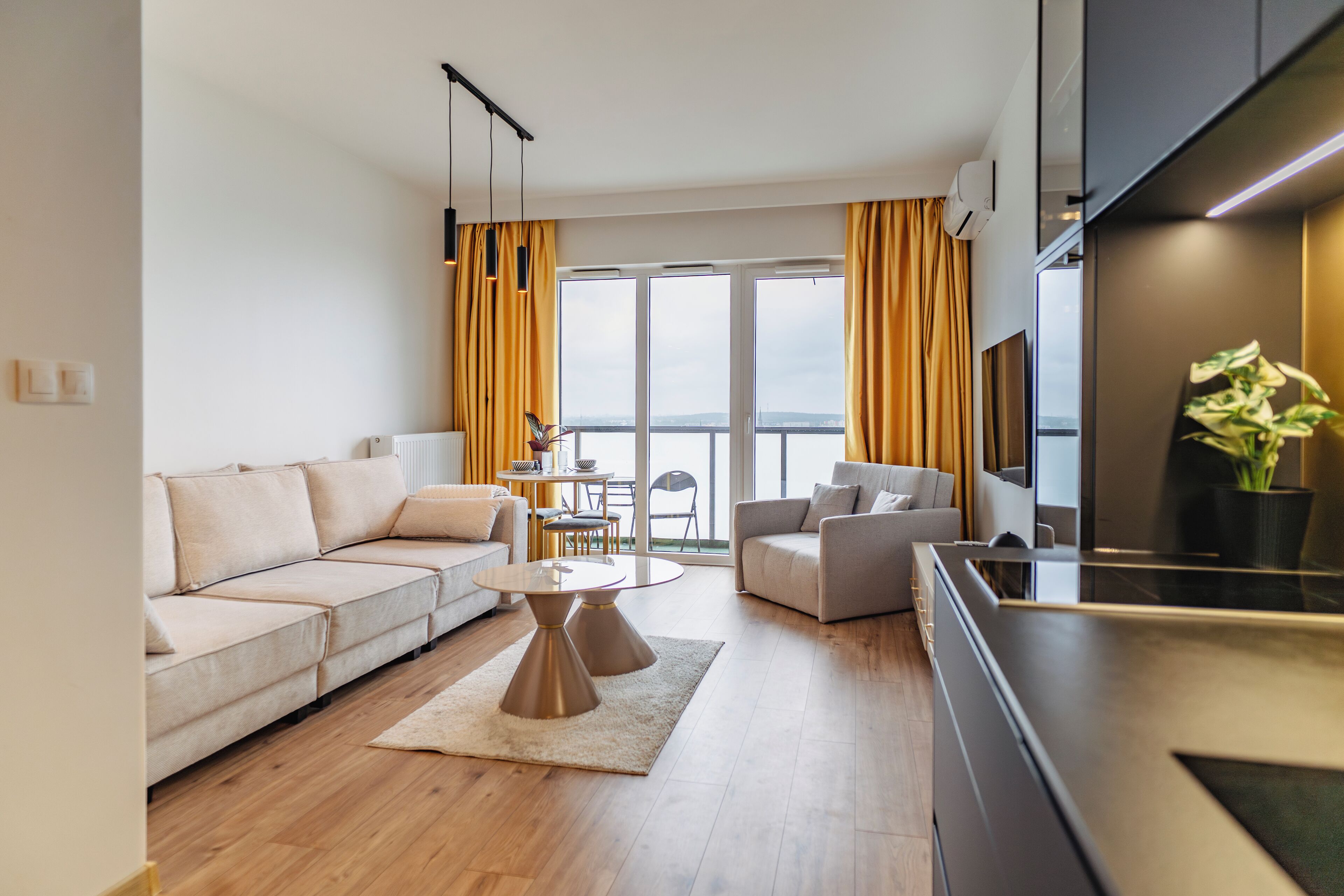 A modern living room with a sofa, coffee table, and a view of the outdoors.