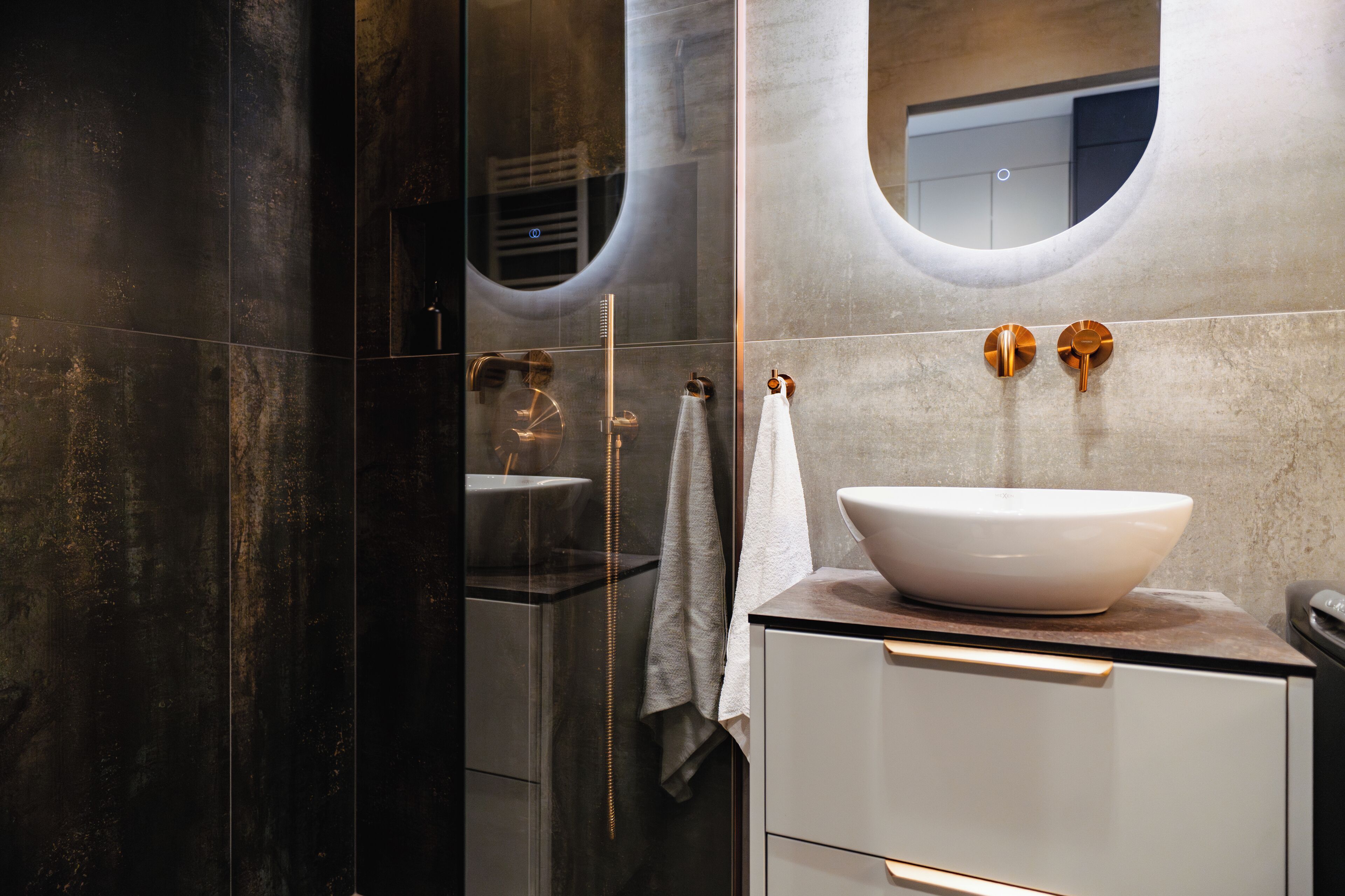 A modern bathroom with a large mirror, a white sink, and a glass shower enclosure.