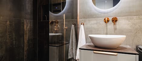 A modern bathroom with a large mirror, a white sink, and a glass shower enclosure.