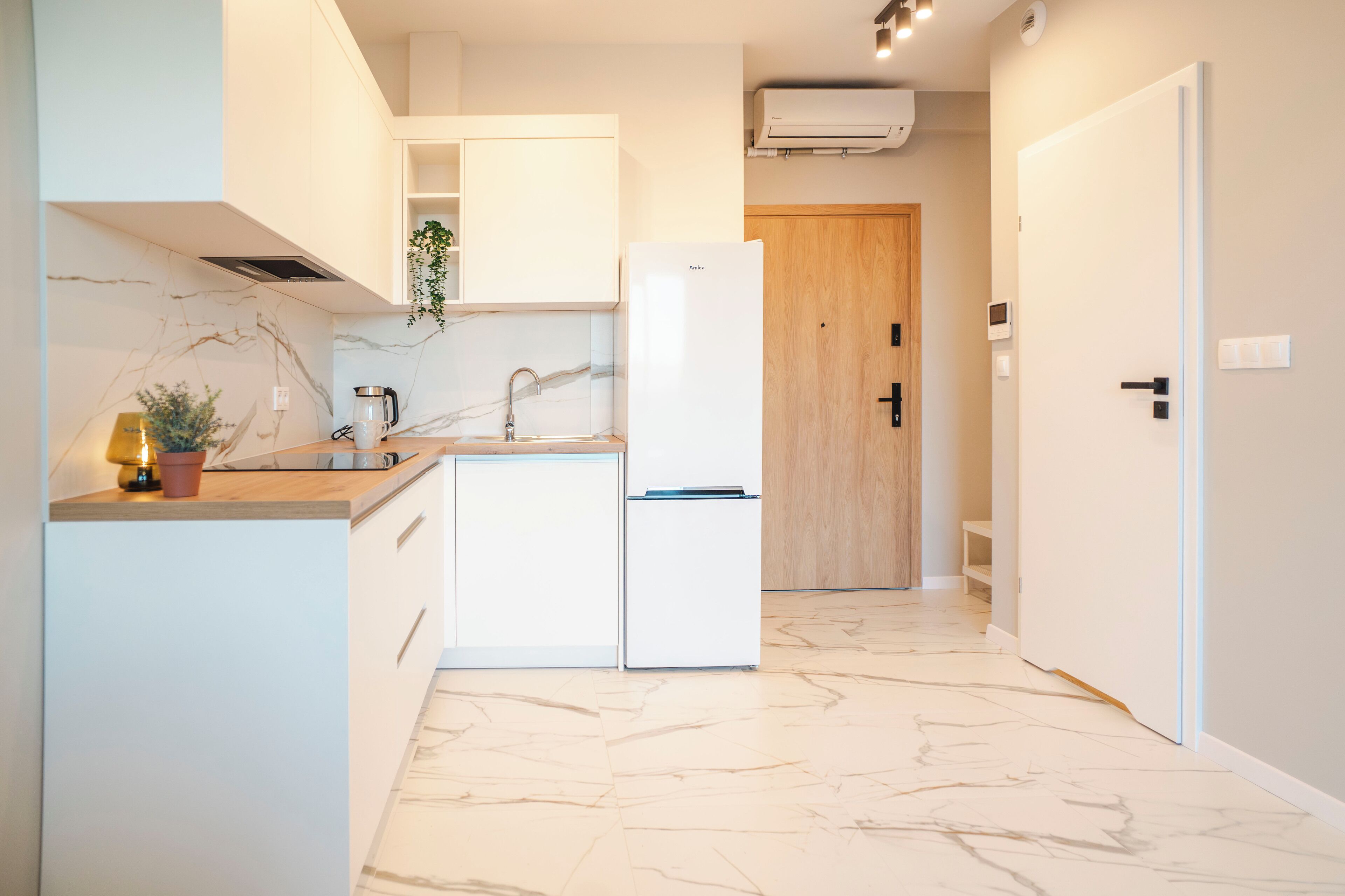 A modern kitchen with white cabinetry, a marble backsplash, and a built-in oven.