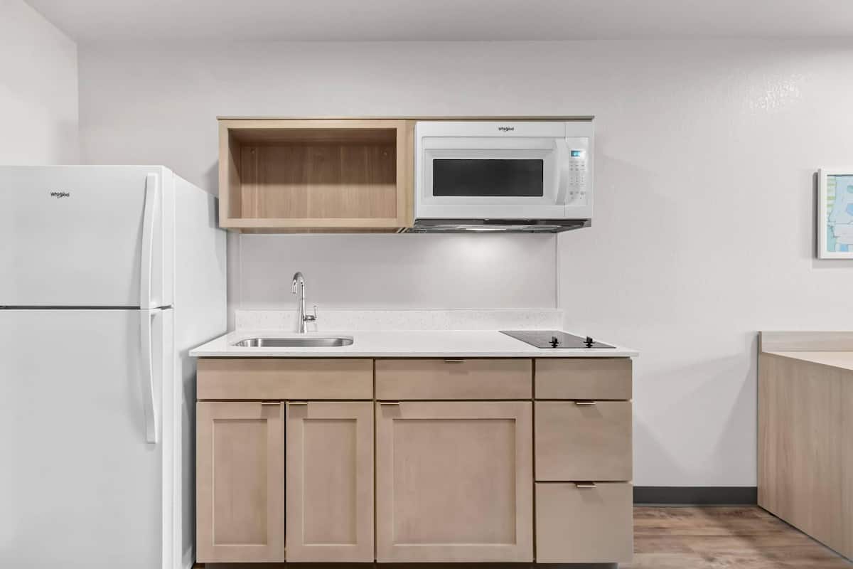 A compact kitchen with a built-in microwave, a sink, and wooden cabinets.
