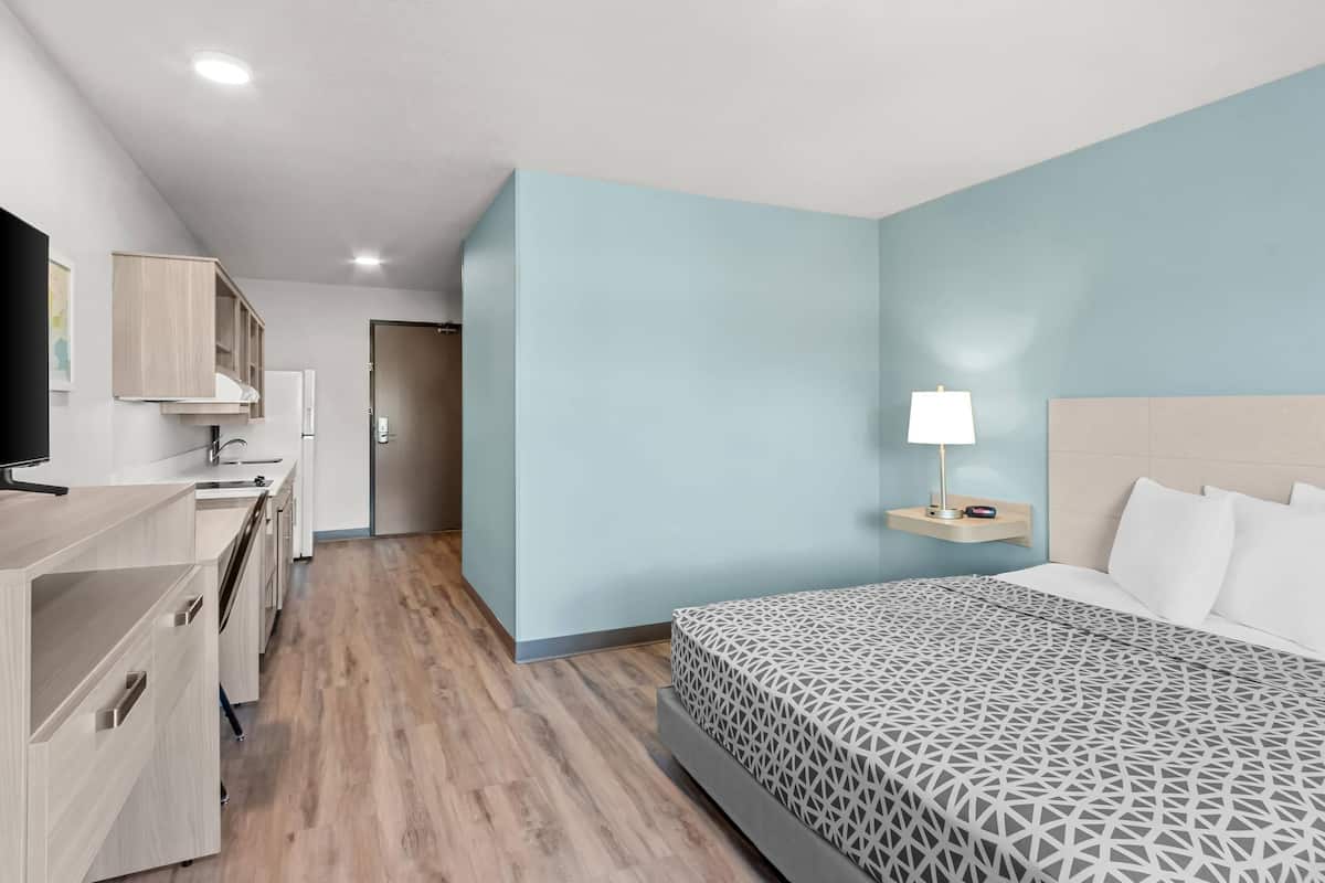A modern hotel room with a bed, bedside table, and a TV.