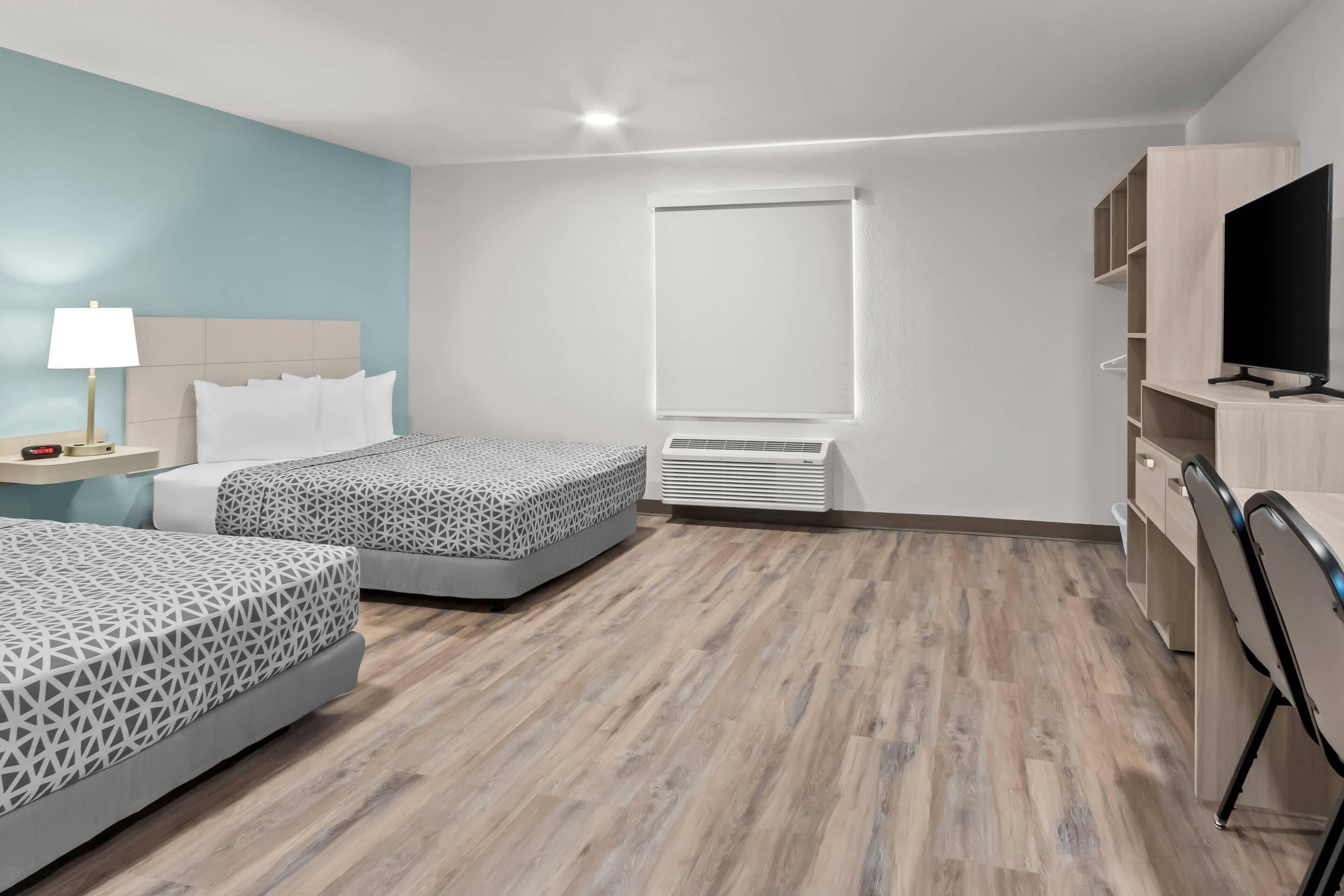 Una habitación de hotel con dos camas, televisión, escritorio y ventana.