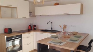 Eine moderne Küche mit Geschirrspüler, Spüle und Essbereich mit Tisch für vier Personen.