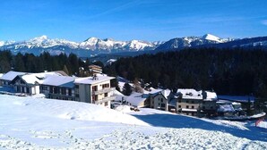 Schneebedeckte Landschaft mit Gebäuden und Bergen im Hintergrund.