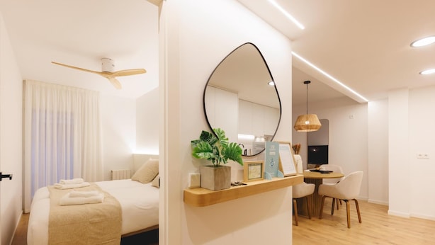 A modern hotel room with a bed, a desk, and a dining area. - Bravissimo Pou Rodó, 2 bedrooms and bike friendly (Girona)