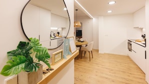 A modern kitchen with white cabinets, a wooden countertop, and a large mirror. There is a dining area with a table and chairs, and a plant on the counter. - Bravissimo Pou Rodó, 2 bedrooms and bike friendly (Girona)
