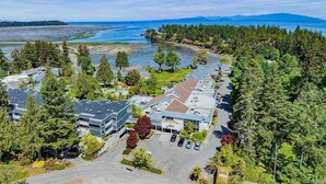 An aerial view of a coastal hotel with multiple buildings, parking areas, and dense surrounding trees. - Oceanside Gardens One Bedroom Ground Floor w/ Kitchen at Pacific Shores Resort! (Nanoose Bay)