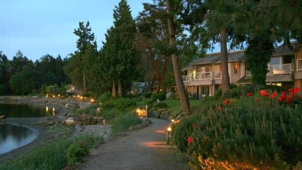A pathway leading to a building with a pond and trees. - Oceanside Gardens One Bedroom Ground Floor w/ Kitchen at Pacific Shores Resort! (Nanoose Bay)