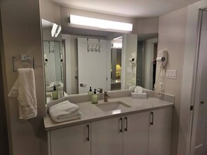 Ein modernes Badezimmer mit einem großen Spiegel, einem Waschbecken und einem an der Wand befestigten Fön.