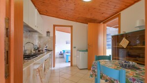 A kitchen with a stove, sink, and cabinets, leading to a dining area with a table and chairs.