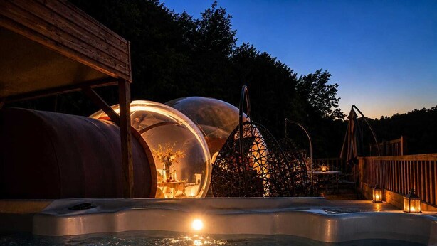 A hot tub surrounded by transparent spherical structures, wooden deck, and a wooden building. - La Bulle Des Anges (Dormir à la belle étoile) (Illoud)