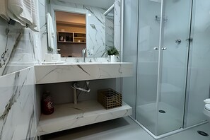 Une salle de bain moderne avec un meuble-lavabo en marbre, une cabine de douche en verre et un lavabo intégré.