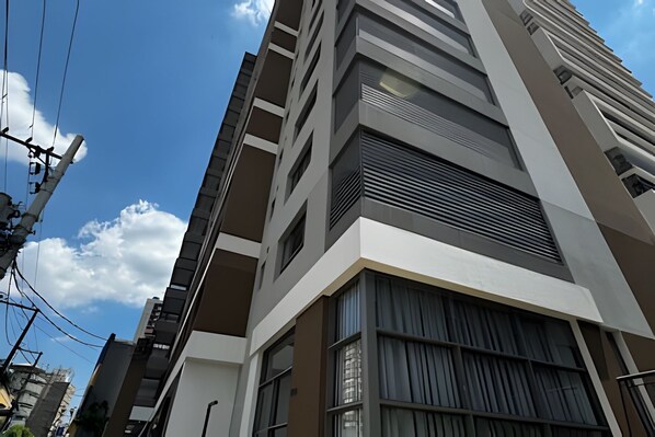 Un immeuble moderne à plusieurs étages, doté de nombreux balcons et de grandes fenêtres.